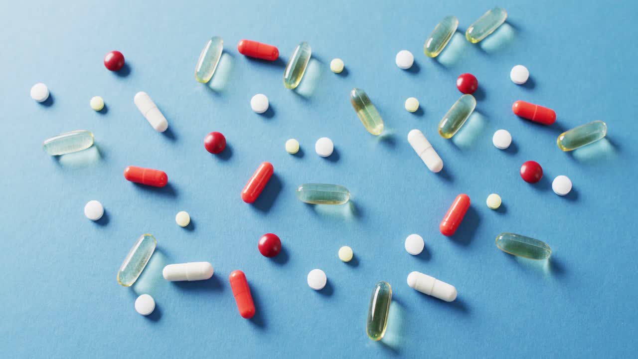vídeo de una variedad de píldoras y cápsulas sobre fondo azul con espacio para copiar