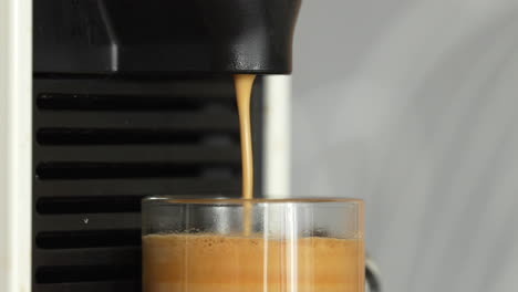 preparar café en una hermosa taza transparente usando una máquina de café espresso automática - primer plano en el borde de la taza y una parte de la máquina de café espresso