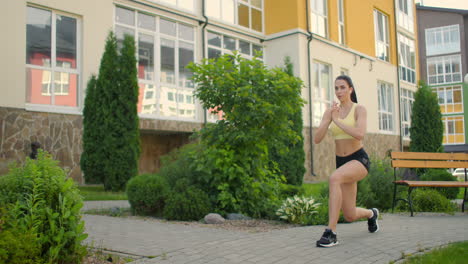 entrenamiento de las piernas y las caderas en el parque de la ciudad. mujer joven hace estocadas en el parque de la ciudad en la pasarela