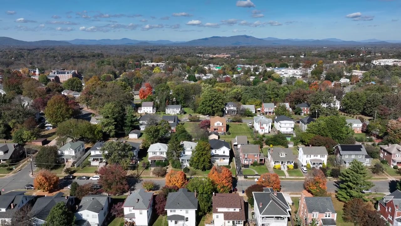 Idilliaco quartiere americano con fila di case in periferia. Giornata di sole con erba verde in giardino e alberi colorati. Giornata autunnale a ottobre. Montagne e colline sullo sfondo. Virginia, USA. Ampia ripresa con drone