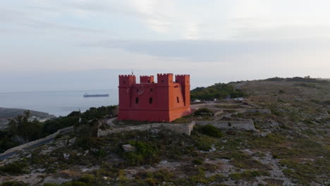 Drohnenschuss-Fliegt-Um-Den-Roten-Turm-Von-St.-Agatha,-Sonniger-Abend-In-Malta