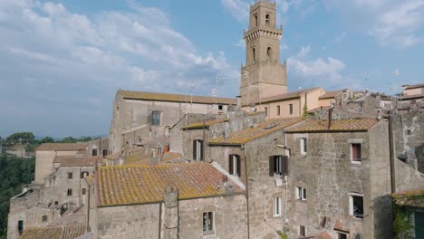 aerial drone view of the hilltop medieval town of pitigliano, tuscany in morning light, flying low over red tile roofs and old buildings, in 4k