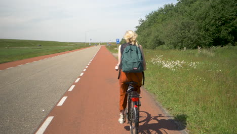 female cyclist with backpack no helmet riding slow motion along a path