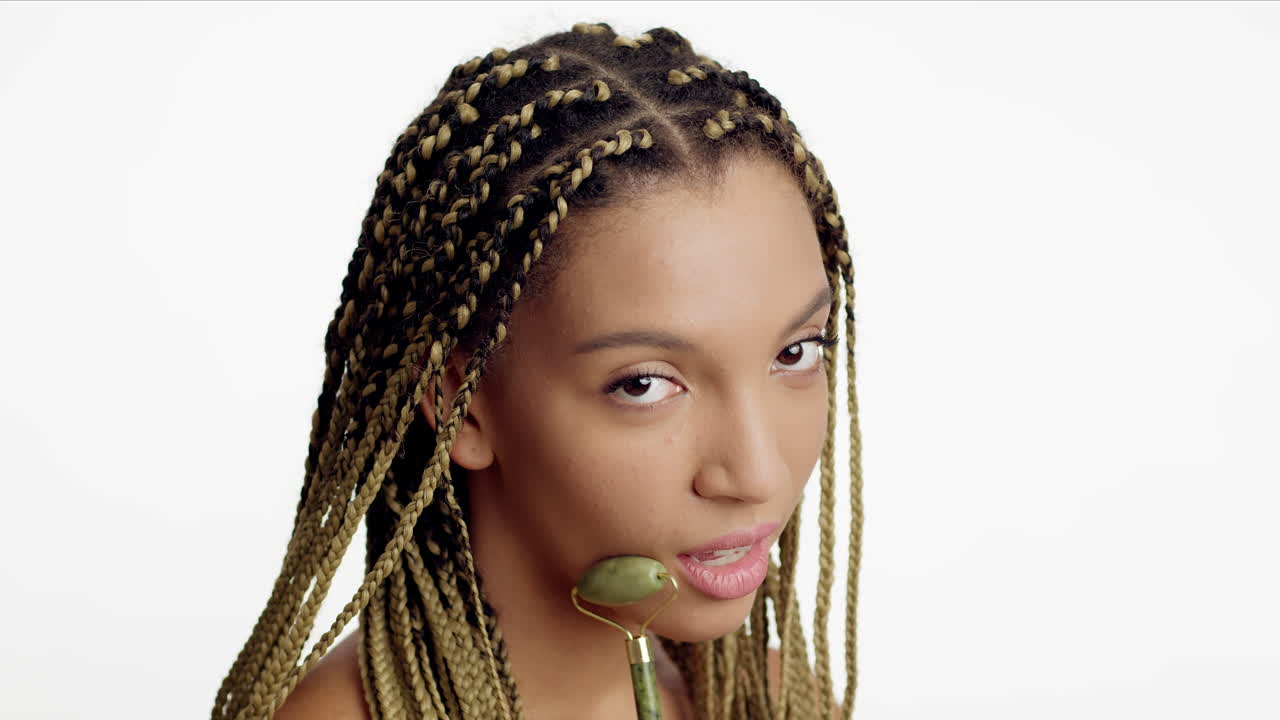 mujer usando un rodillo de jade para el masaje facial