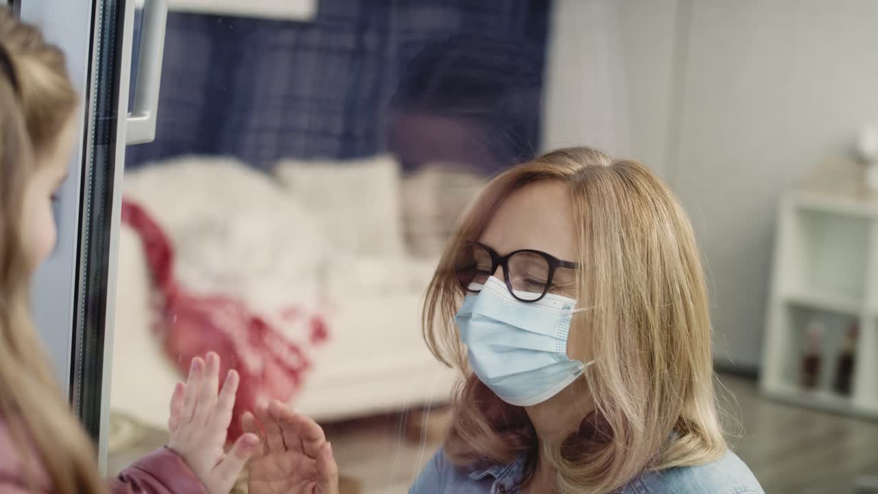 작은 소녀가 창문을 통해 할머니를 보고 있습니다.