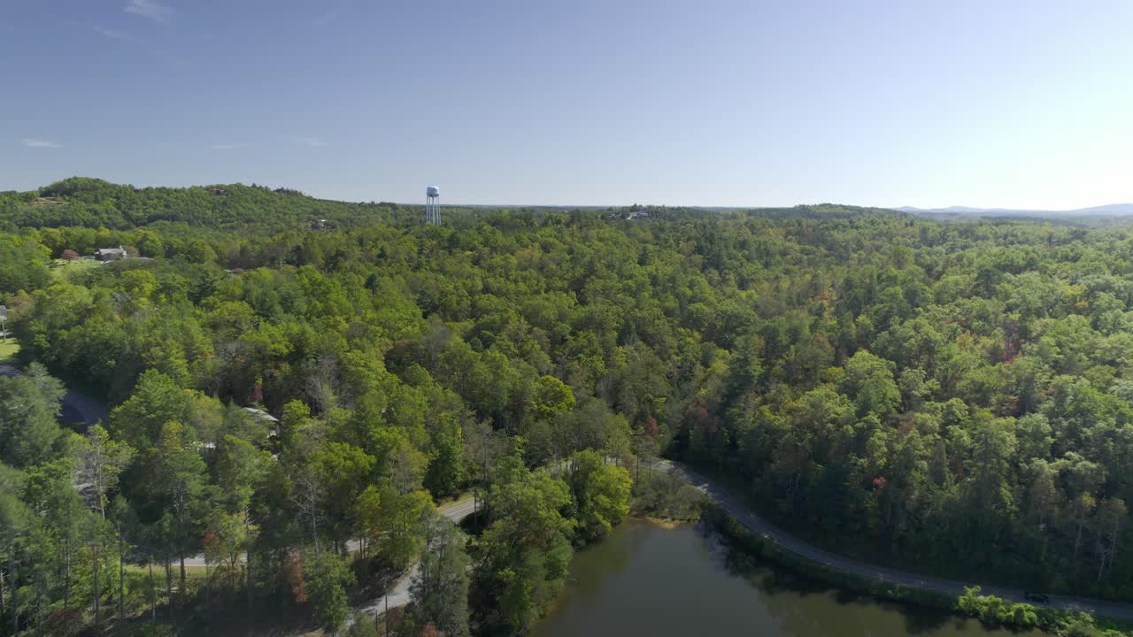 Flying over beautiful Lake Lure and approaching a forest and a water tower
