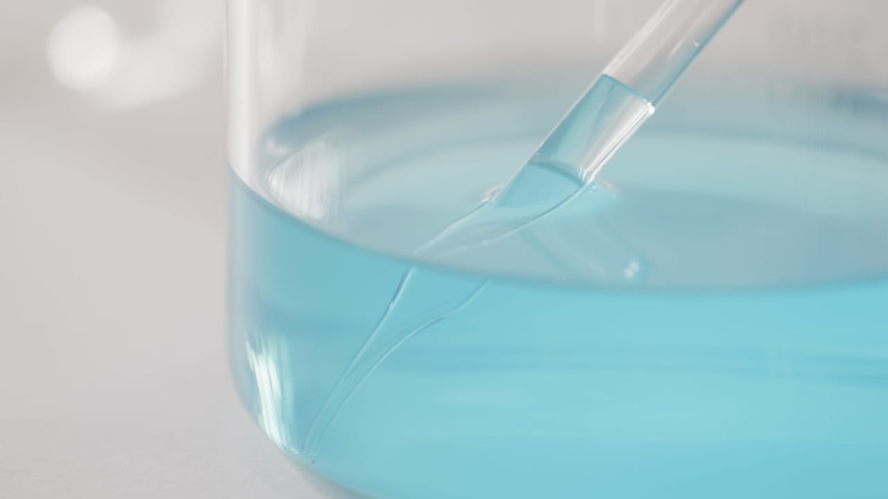 vídeo de un plato de laboratorio de vidrio con líquido azul con espacio de copia en fondo blanco