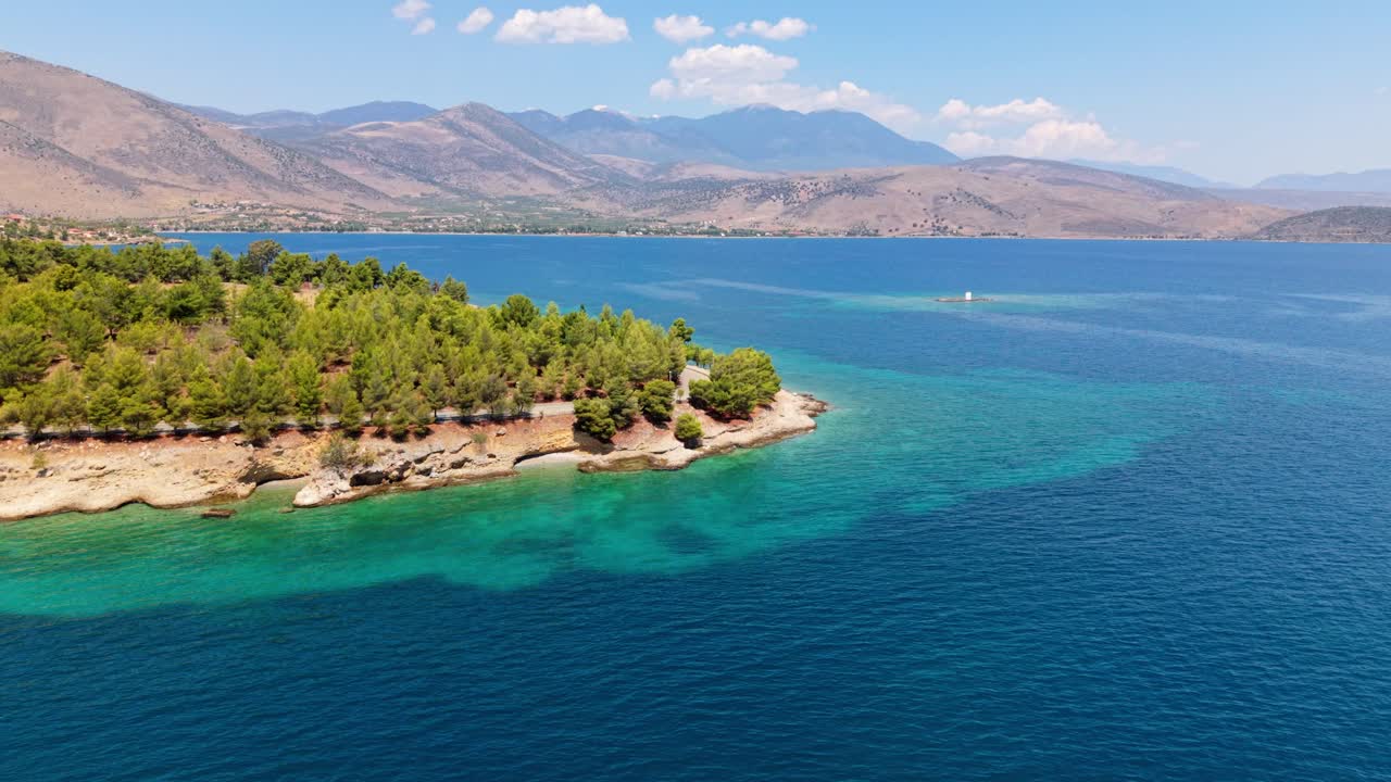 Aerial flyover of calm blue sea and coastal forest stretching along the Greek shoreline