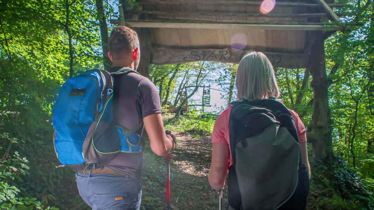 Couple hiking through an archway in a forest