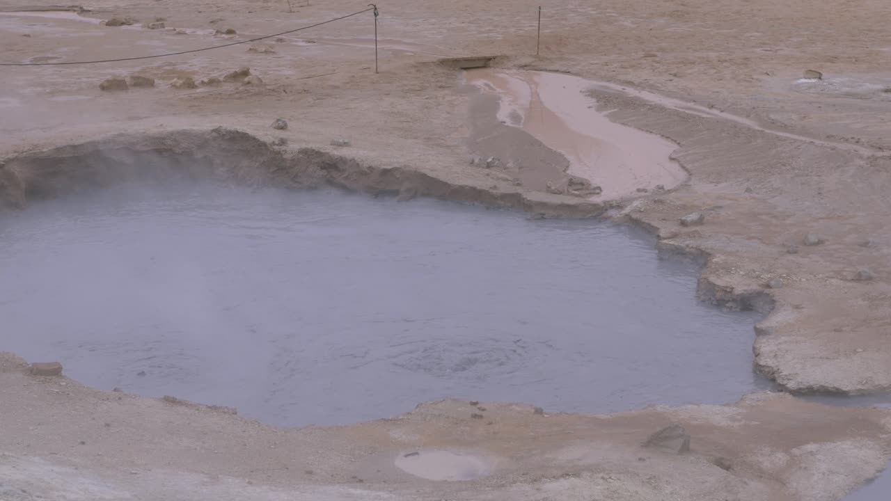 Boiling water in a steaming hot spring surrounded by rocky ground in Iceland's Namaskaro region