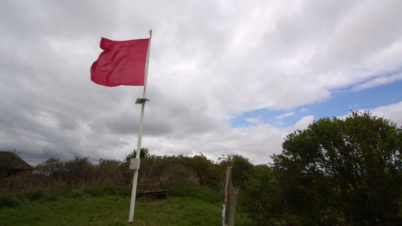 bandera de peligro roja volando en el viento borrasco a la izquierda del cuadro