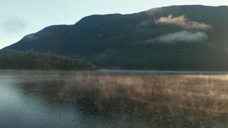 antena del lago de montaña brumoso al amanecer volando hacia adelante sobre el agua