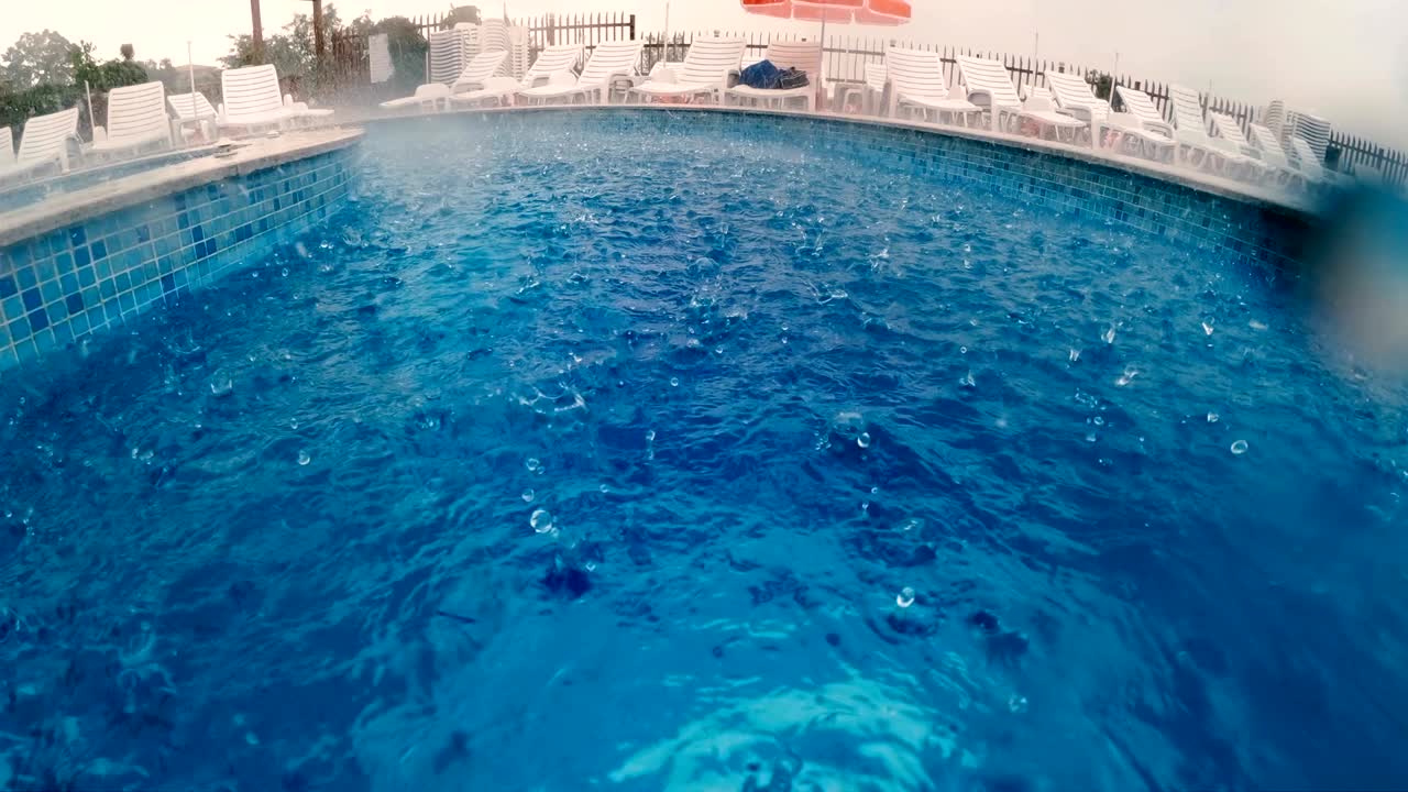 lluvia fuerte en la superficie del agua de la piscina, movimiento lento