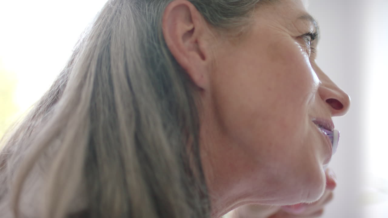 Caucasian woman with grey hair showing wrinkles, looking away