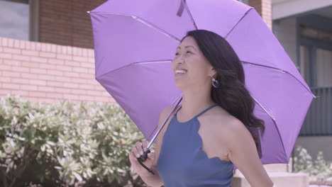 asian woman walks down the street with a purple umbrella on a sunny day