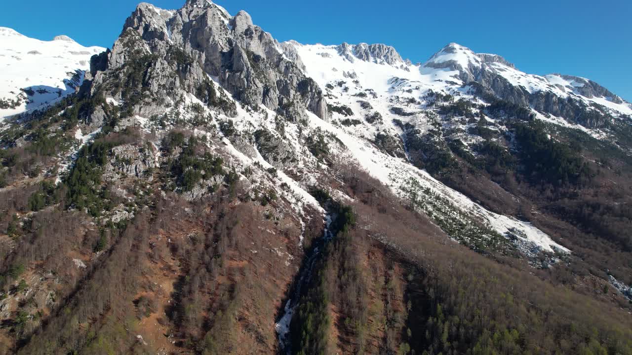volando hacia el pico épico de la montaña cubierto de nieve blanca, hermosos alpes albaneses