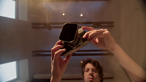 person holding a vintage camera, reflected in a mirror