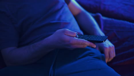 Hand-held-shot-of-a-man-resting-on-the-couch-reaching-for-the-tv-remote