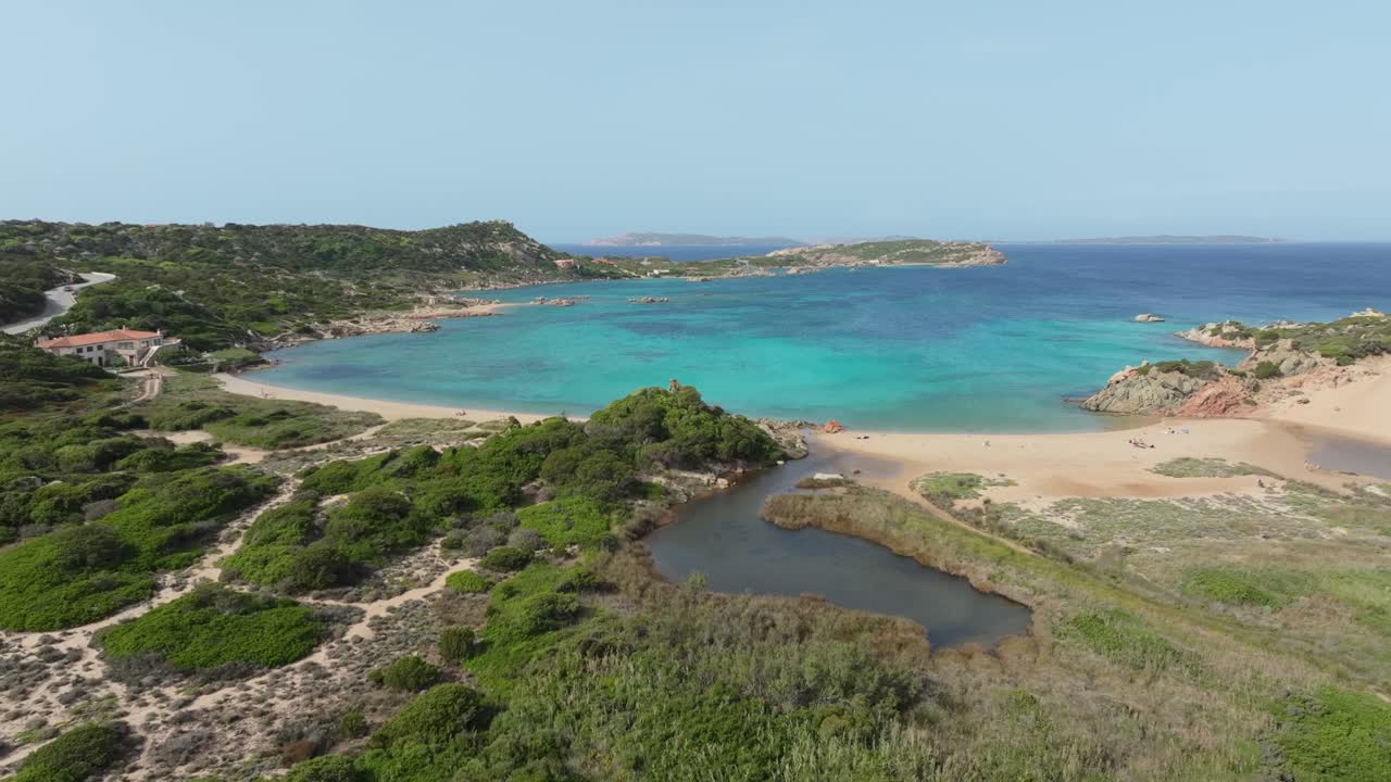 Fantastisk luftperspektiv af en bugt på Sardinien. Kameraet flyver over et frodigt grønt landskab mod det uberørte turkise Middelhav.