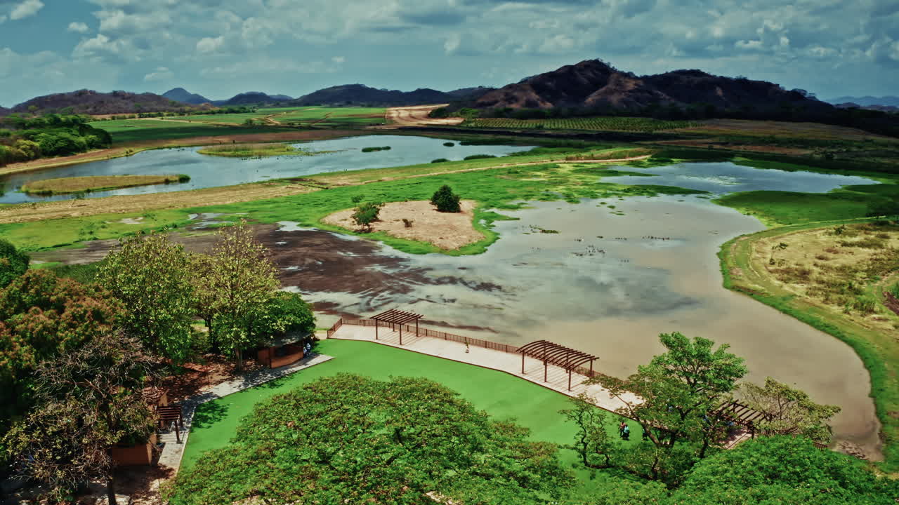 Aerial View of a Serene Wetland Park with Lakes, Lush Greenery, and Hills