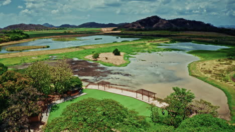 aerial view of a serene wetland park with lakes, lush greenery, and hills