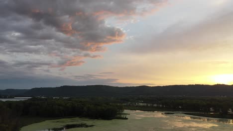 puesta de sol sobre un valle de río con pantano y colinas