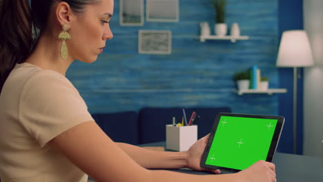 mujer trabajando en un escritorio usando una computadora de tableta de pantalla verde simulada
