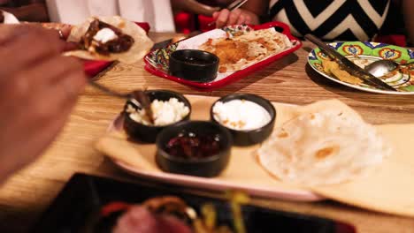 diners assemble and savor tlayudas with various toppings in a warmly lit mexican restaurant setting