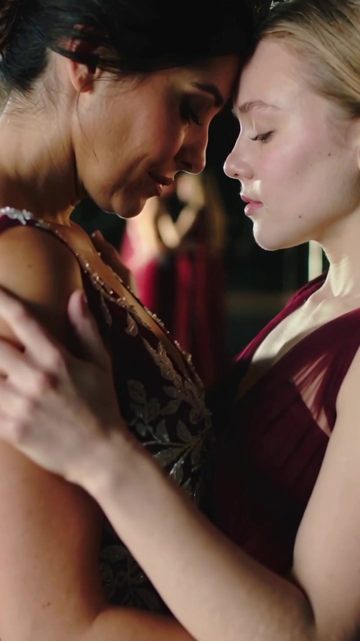 Vertical video: Hugging, two women leaning close in prep, mirror showing burgundy gowns, necklace