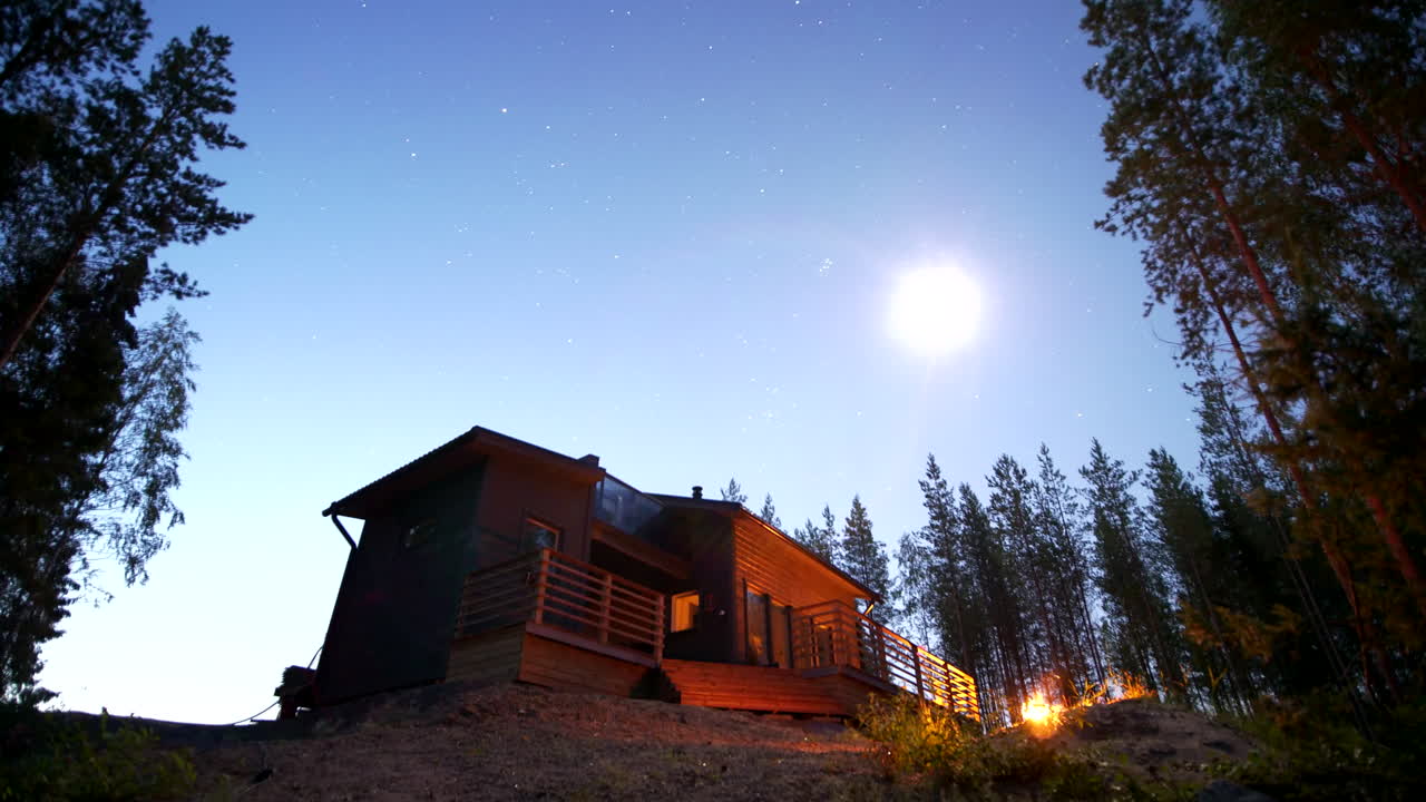 Time-lapse af stjerner om natten med et hus på landet