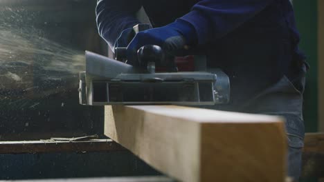 macro close up of professional carpenter working on woodworking machines in a workshop of wood factory.