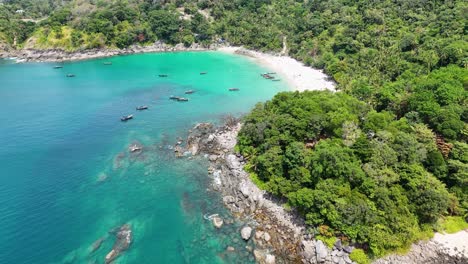 drone footage captures phuket's lush greenery and turquoise waters, showcasing rocky shores and serene beaches under bright daylight