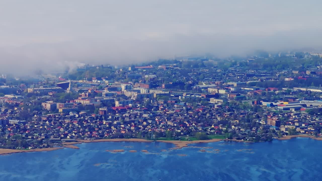 Cinematic tele view of Liepaja Latvia showing lake shoreline and heavy sea fog