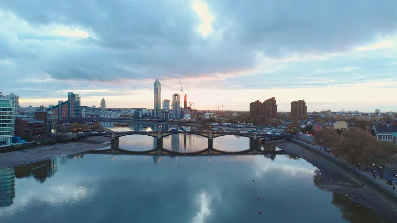 Voorwaartse drone-opname van verkeer op de Battersea Bridge en Chelsea Harbour, Londen bij zonsondergang.