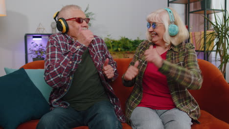 joyful senior grandparents man woman listening music dancing disco fooling around having fun at home