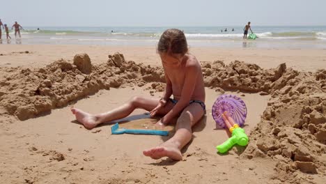 praia da rocha baixinha, portogallo - una ragazzina che si diverte con la sabbia sulla spiaggia - da vicino