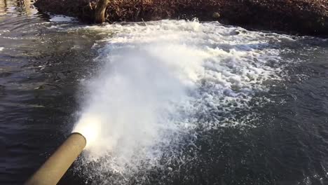 slow motion water pours from an iron rusty pipe