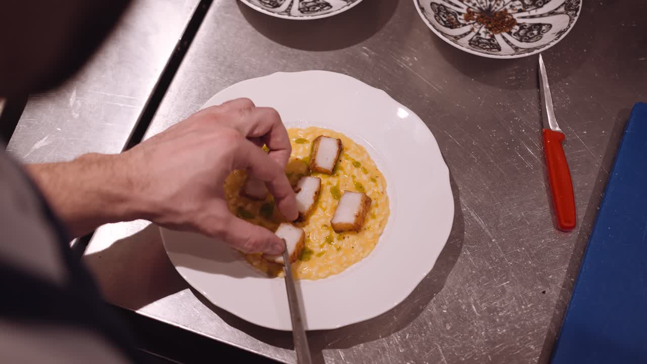 cocinero en un restaurante pone los trozos de pollo frito en el plato blanco con pasta