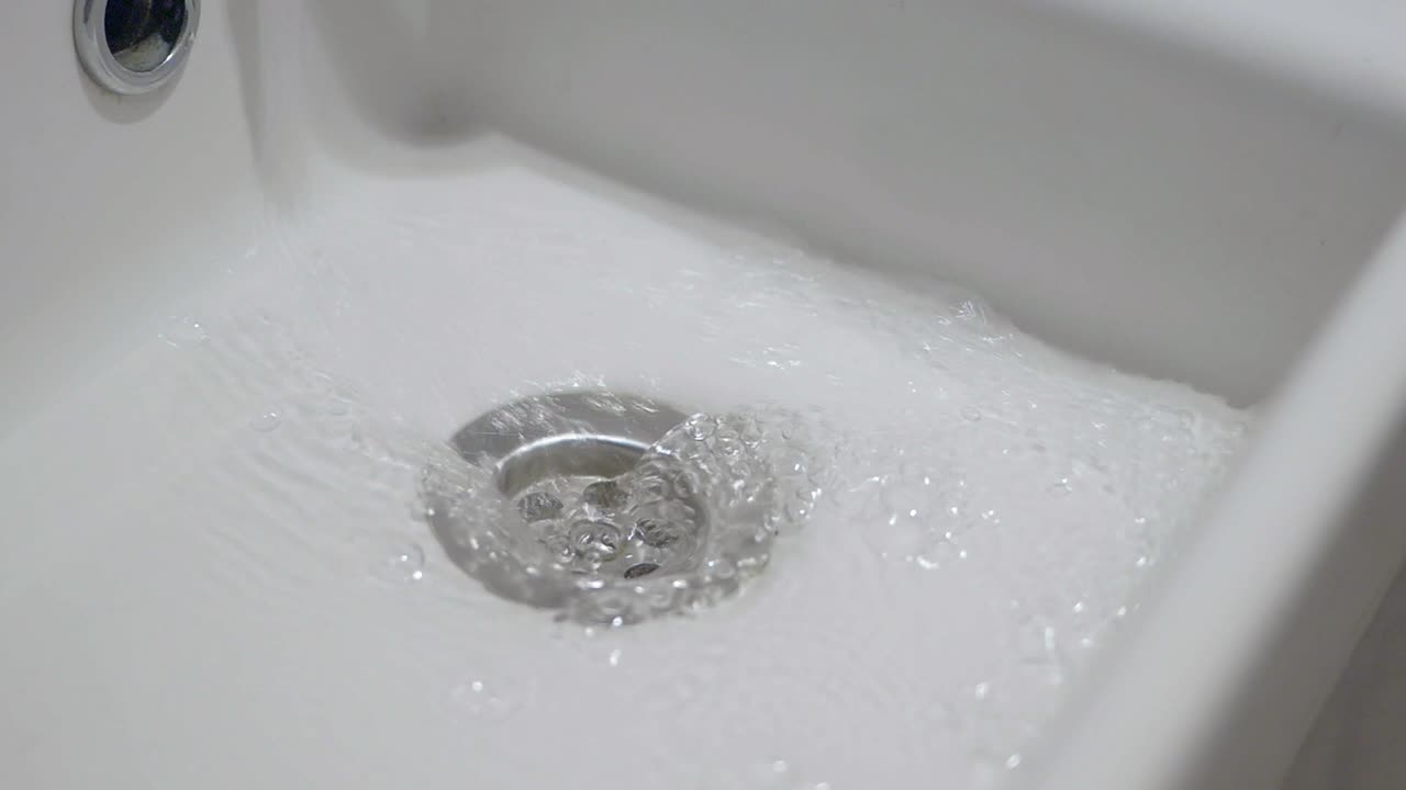 primer plano del agua que fluye por un desagüe del fregadero