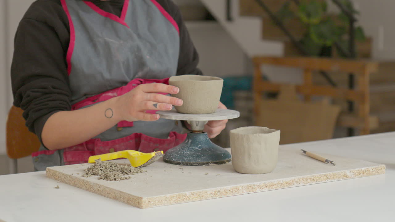 una hábil artesana teje magia con arcilla en una rueda giratoria, creando una obra maestra en su elegante estudio