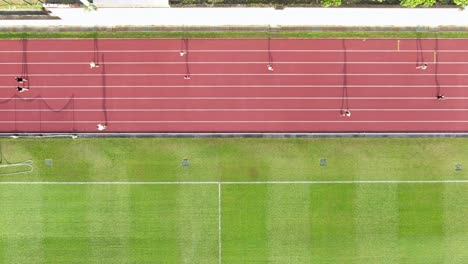 People-during-Early-morning-Jogging-on-a-racetrack-with-long-starched-silhouettes,-Aerial-view