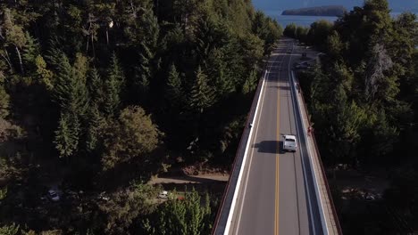 aerial shot flying over a bridge in villa la angostura while cars are driving in patagonia argentina