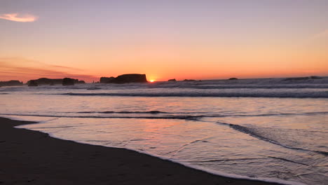 colorful sunset at the oregon coast in bandon with sea stacks in the background, and waves coming and going