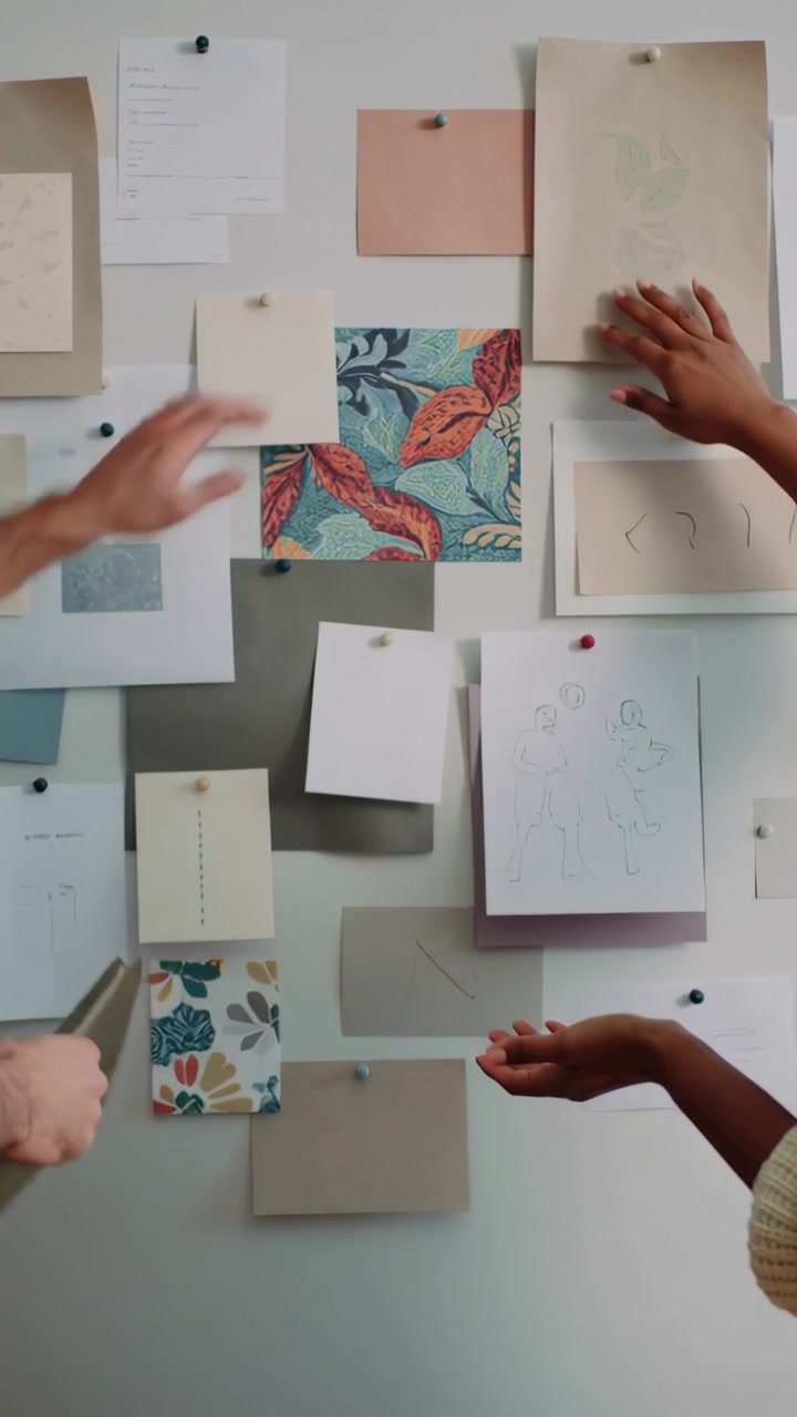 Vertical video: Reaching left man blue shirt adjusting papers in studio, showing swatch, planning