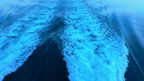 wake trail behind a boat on the open sea, showcasing vibrant blue waters and the movement of water under bright sunlight