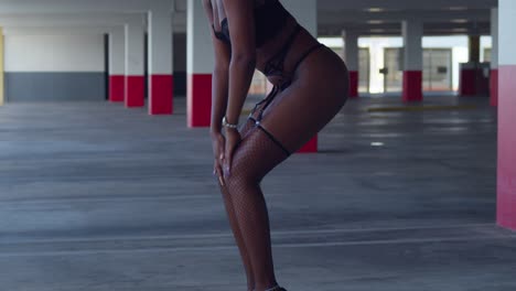 ascending camera movement of a black girl in sexy lingerie in a aprking garage