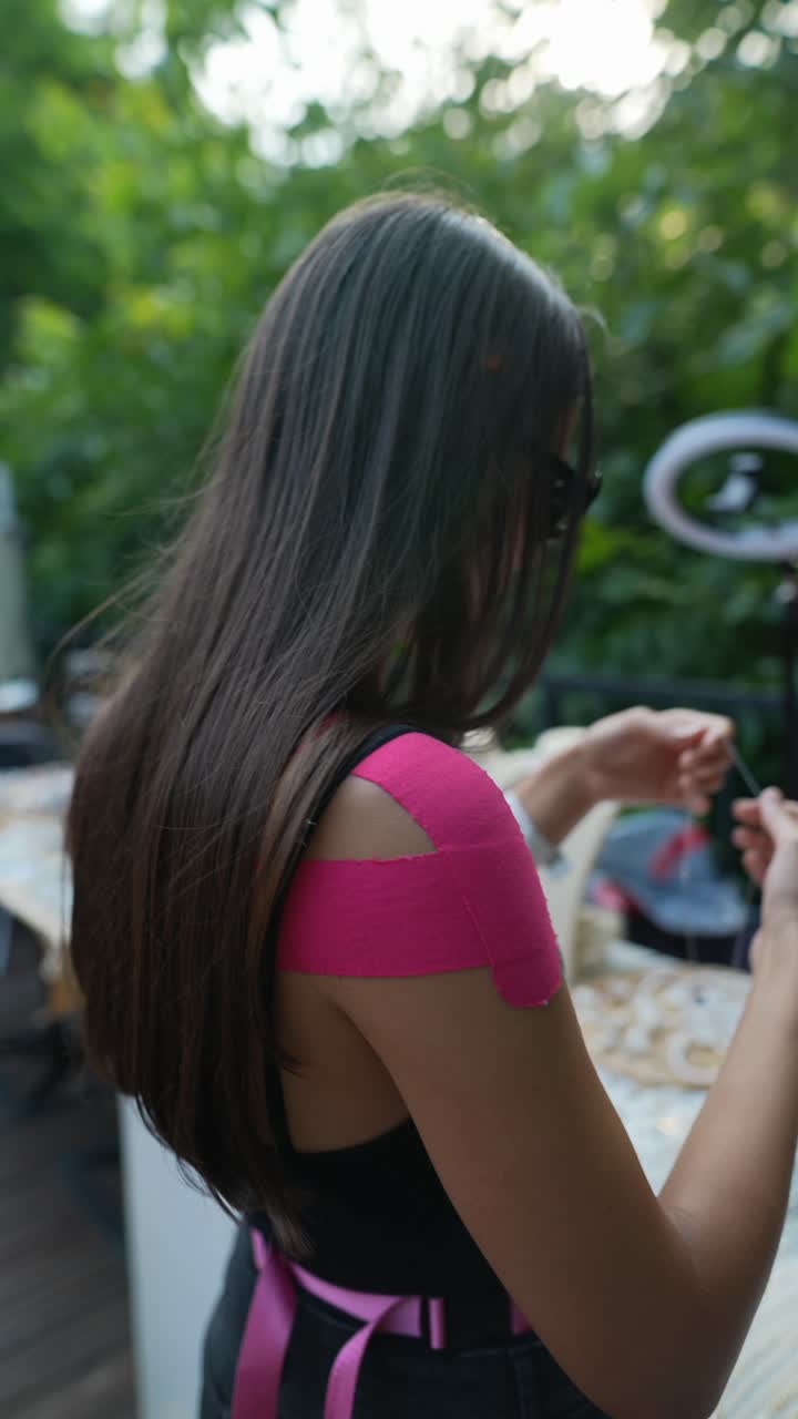 여성이 보석을 만들고 어깨 테이프를 적용합니다.