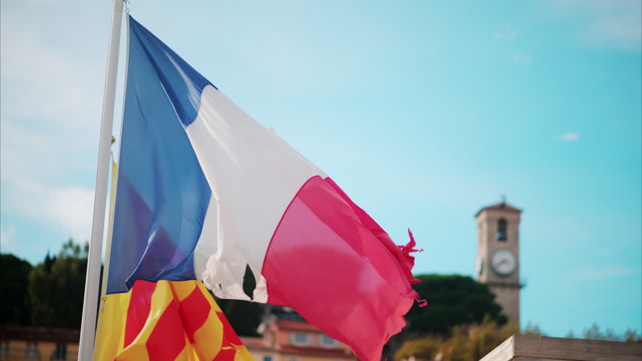 Una bandiera francese strappata che sventola con la città di Cannes, Francia sullo sfondo