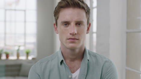 young handsome man portrait of red head guy looking serious pensive at camera in contemporary apartment background