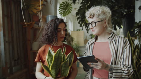 girls using tablet and speaking during workday in flower shop